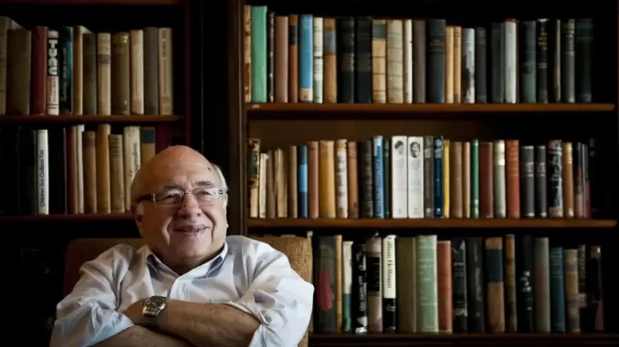 corpo-de-luis-fernando-verissimo-assembleia-rs-velorio Imagem de Luís Fernando Verissimo sorrindo, sentado em frente a uma estante cheia de livros, durante despedida na Assembleia RS.