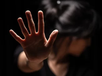 Mulher com expressão triste e mão estendida, simbolizando a denúncia de estupro, em destaque para a redução de 3,1% nas denúncias em julho no Estado de São Paulo.