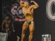 Atleta de bodybuilding em competição de fisiculturismo na NPC WorldWide, exibindo músculos definidos e postura de apresentação no palco.