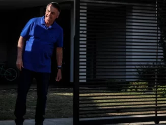 Imagem de um homem em frente a uma residência, com detalhes de uma grade de ferro na porta e ambiente externo, relacionado à notícia sobre o PGR que descartou PF na casa de Bolsonaro e mantém prisão domiciliar do ex-presidente.