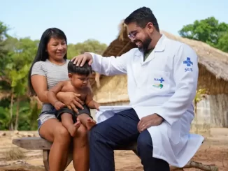 Profissional de saúde do programa Mais Médicos interagindo com uma criança e uma mulher em zona rural brasileira, promovendo cuidado e atenção à saúde.