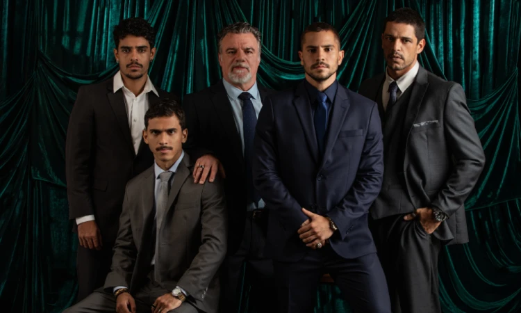 Imagem dos atores principais da série Os Donos do Jogo, revelada pela Netflix, com cenário de cortina verde escura ao fundo. A série é destaque na divulgação das primeiras imagens.