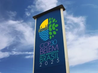 Placa comemorativa do Projeto Copa Belo Horizonte Amazonas Brasil 2025 com logo colorido, céu azul e nuvens ao fundo.