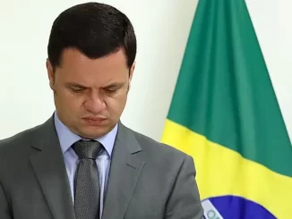 Anderson Torres, condenado a 24 anos de prisão pelo STF, em sessão oficial com bandeira do Brasil ao fundo.