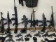Imagem mostrando diversas armas apreendidas pela Polícia Militar no Rio de Janeiro até 2025, totalizando 500 fuzis confiscados.