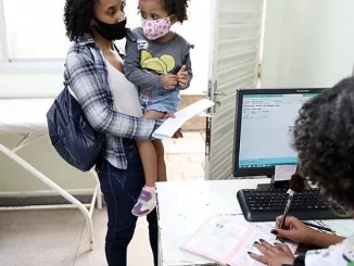 Mãe e criança com máscaras facial aguardam atendimento em UPA do RJ devido ao aumento de casos de Covid em crianças, refletindo aumento de atendimentos infantis com sintomas de Covid nas unidades de saúde.