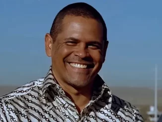 Ator Raymond Cruz de 'Breaking Bad' sorrindo ao ar livre após suposta prisão por agressão, destacado por sua expressão facial e camisa estampada.