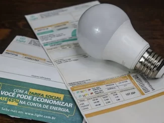 Contas de luz com bandeira vermelha que mantém a tarifa mais cara em setembro, incluindo um boleto de energia e uma lâmpada, ilustrando o aumento na conta de luz.