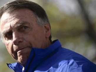 Bolsonaro deixando a prisão domiciliar após mal-estar e indo ao hospital, expressão séria em ambiente ao ar livre.