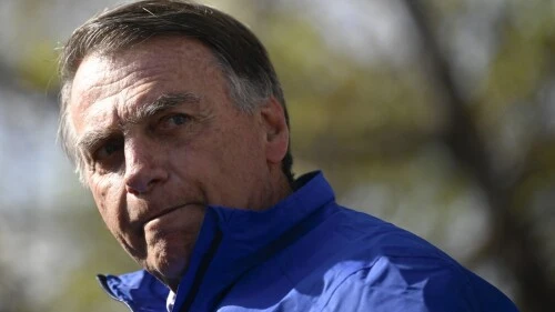 bolsonaro-deixa-prisao-domiciliar-mal-estar-hospital Bolsonaro deixando a prisão domiciliar após mal-estar e indo ao hospital, expressão séria em ambiente ao ar livre.