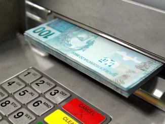 Brasileiros resgatam R$ 310 milhões em valores esquecidos em bancos, representados por uma pilha de notas de 100 reais sendo retiradas de um caixa eletrônico.