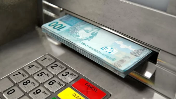brasileiros-resgatam-valores-esquecidos-bancos Brasileiros resgatam R$ 310 milhões em valores esquecidos em bancos, representados por uma pilha de notas de 100 reais sendo retiradas de um caixa eletrônico.