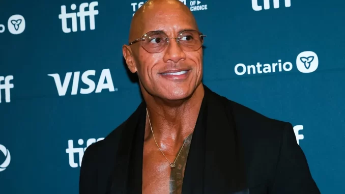 dwayne-johnson-idoso-galinha-lizard-music Imagem do ator Dwayne Johnson representado como um idoso de 70 anos em 'Lizard Music', vivendo uma amizade com uma galinha, em um evento de cinema.