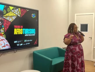 Lançamento do novo guia racial pelo Embratur para impulsionar o afroturismo no Brasil, apresentando uma líder falando em evento de divulgação.
