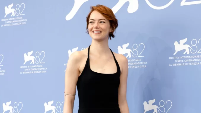 emma-stone-diz-acreditar-em-extraterrestres-festival-veneza2023 Emma Stone durante o Festival de Veneza 2023, dizendo que acredita em extraterrestres, em destaque na origem da imagem. Ela usa vestido preto e sorri para a câmera, com fundo azul do evento.