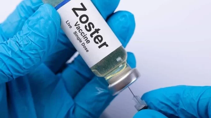 estudo-vacina-zoster-reduz-risco-doenca-cardiovascular Vacina Zoster sendo preparations por uma pessoa usando luvas azuis, relacionada ao estudo que indica que a vacina de zóster reduz risco de AVC e infarto.