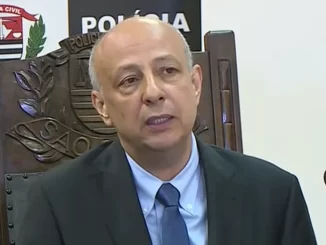 Ex-delegado-geral da Polícia Civil de São Paulo, Ruy Ferraz Fontes, vítima de homicídio a tiros em Praia Grande, durante entrevista ou declaração, com fundo de logotipo da Polícia Civil de São Paulo.