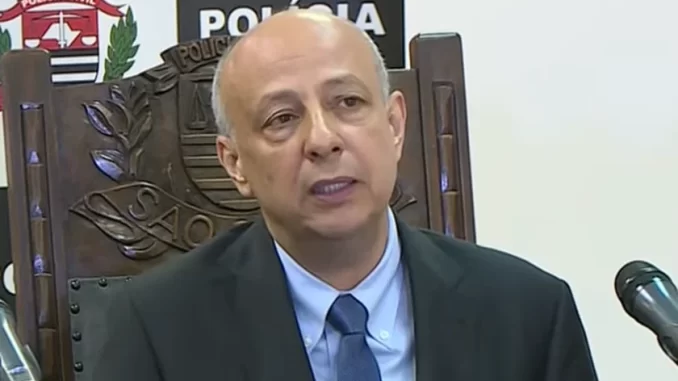 ex-delegado-geral-policia-civil-sp-ruy-ferraz-fontes-morto-tiros-praia-grande Ex-delegado-geral da Polícia Civil de São Paulo, Ruy Ferraz Fontes, vítima de homicídio a tiros em Praia Grande, durante entrevista ou declaração, com fundo de logotipo da Polícia Civil de São Paulo.