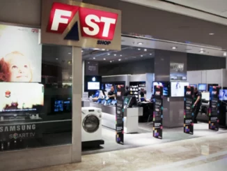 Imagem da loja FastShop dentro de shopping com destaque para o logo vermelho e branco da FastShop, e várias telas de TV e caixas de automação ao fundo.