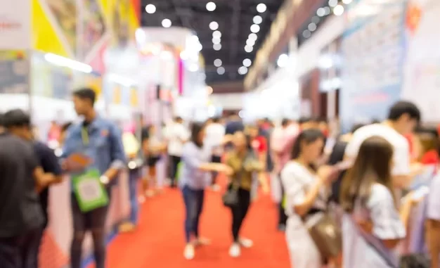 feiras-e-exposicoes-setor-que-movimenta-bilhoes-e-empregos-brasil-mundo Imagem de uma feira ou exposição movimentada, com diversas pessoas interagindo e explorando diferentes stands em um ambiente vibrante e cheio de energia, destacando a importância do setor que movimenta bilhões e gera milhões de empregos no Brasil e no mundo.