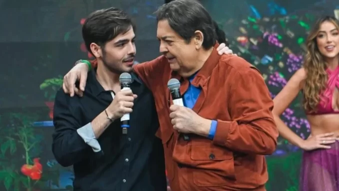 Filho de Faustão falando sobre recuperação, cautela e fisioterapia em evento com o apresentador e uma dançarina no fundo