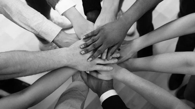 forum-brasil-diverso-2025-saude-mental-sustentabilidade-jpg Imagem em preto e branco de várias mãos de diferentes pessoas empilhadas juntas, simbolizando união e diversidade, em um contexto relacionado ao Fórum Brasil Diverso 2025 que destaca saúde mental e sustentabilidade no mundo corporativo.
