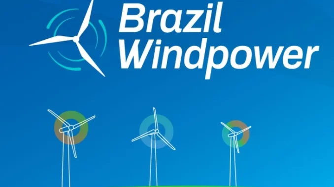 lideres-brazil-windpower-2025-expand-eolica-brasil-jpg Imagem de líderes do Brazil Windpower 2025 discutindo a expansão da energia eólica no Brasil, com silhuetas de aerogeradores ao fundo.
