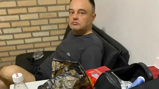 policia-federal-captura-condenados-por-bomba-no-aeroporto-de-brasilia Polícia Federal captura condenado por bomba no aeroporto de Brasília, homem sentado em sala, cercado de objetos por investigação.