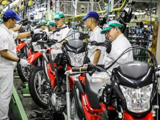 Fábrica de motocicletas atingindo melhor desempenho de produção em agosto com equipes de trabalhadores monitorando a linha de montagem de motos.