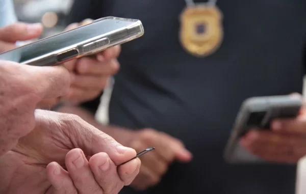 sp-notifica-usuarios-reativaram-celulares-roubados-prazo Policial verificando celular de uma pessoa que reativou celular roubado, em operação no estado de São Paulo, com foco na notificação e prazo para reativação.