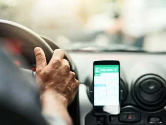 Imagem de um motorista de aplicativo usando um smartphone no painel do carro, ilustrando o tema do julgamento do STF sobre vínculo de motoristas e plataformas digitais.