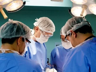 Cirurgiões realizando uma cirurgia de emergência em paciente, amparados por equipe médica em centro cirúrgico, destacando a decisão do STJ de obrigar planos de saúde a cobrir emergências em cirurgias estéticas.