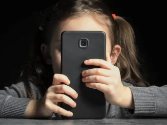 Criança usando smartphone, destacando o uso excessivo de telas na infância e seus riscos ao desenvolvimento infantil.