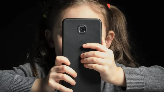 uso-excessivo-telas-infancia-alerta-desenvolvimento Criança usando smartphone, destacando o uso excessivo de telas na infância e seus riscos ao desenvolvimento infantil.