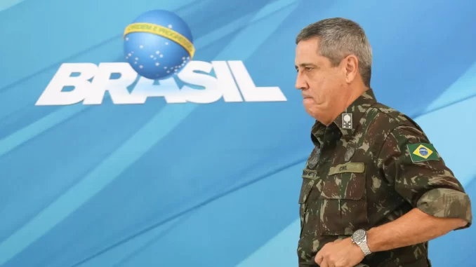 walter-braga-netto-pena-26-anos-stf-jpg Walter Braga Netto, vestido de uniforme militar, em evento relacionado ao Brasil, com fundo que exibe o logo do Brasil e texto sobre pena de 26 anos pelo STF.