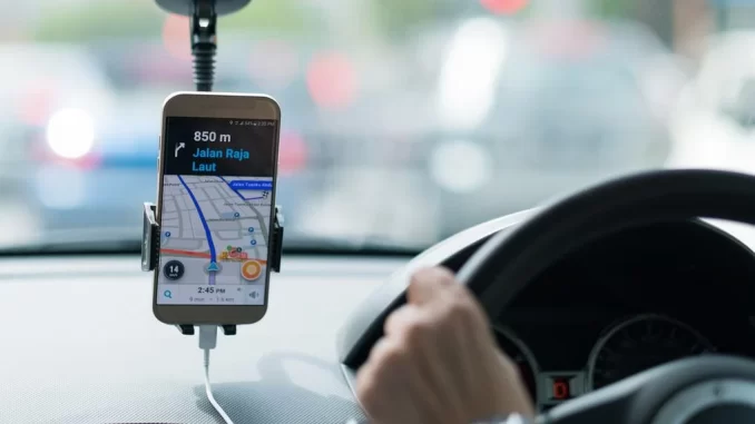 navegacao-por-gps-no-carro-jpg Imagem de um celular com GPS indicando rota em uma navegação por aplicativo dentro de um carro, na manhã, em trânsito na cidade.