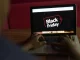 Pessoa acessando a pesquisa do Procon-SP sobre hábitos de compra na Black Friday em um laptop com a tela exibindo o logo de Black Friday.