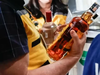 Homem segurando garrafa de álcool adulterado ligado à intoxicação por metanol em São Paulo, no contexto de sexta morte suspeita