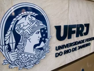 Imagem da fachada da Universidade Federal do Rio de Janeiro (UFRJ), destacando seu logo e o nome da instituição, com ênfase na inclusão de vagas para pessoas trans.