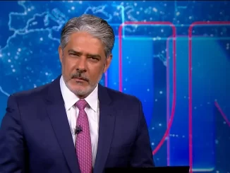 William Bonner se despede da bancada do Jornal Nacional após 29 anos, com expressão séria, durante transmissão ao vivo em estúdio de notícias.