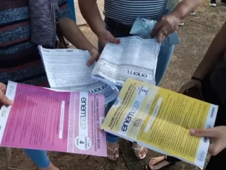 Estudantes discutindo informações sobre o Enem 2021, destacando a abstenção de 27% na prova, que mantém a média anual nacional, em um cenário de alta participação.