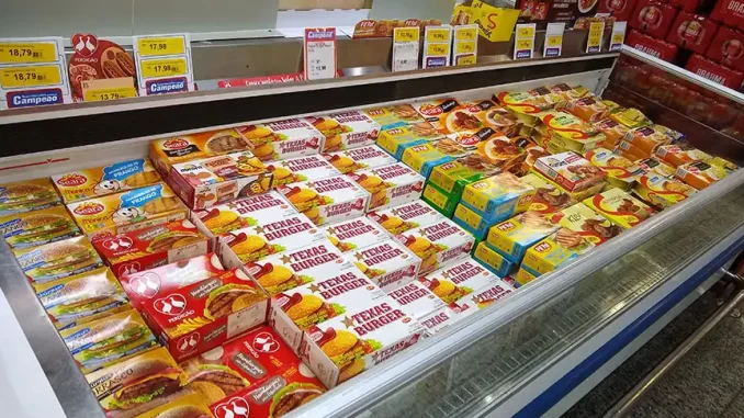 alimentoseultraprocessadossupermercado Prateleira de alimentos ultraprocessados em supermercado, destaque para produtos como hambúrgueres e refeições instantâneas, ilustrando o consumo de 23% da dieta no Brasil, conforme pesquisa da USP.