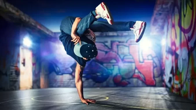 camara-aprova-criacao-dia-nacional-do-hiphop-11-agosto-jpg Jovem dançarino de break dance em posição de equilíbrio em um espaço urbano com arte de grafite nas paredes, celebrando a cultura do Hip-Hop.