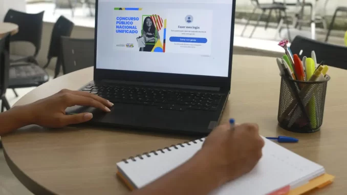 Pessoa verificando a lista de aprovados no Concurso Nacional Unificado no notebook, participando do processo de convocação de 3,9 mil aprovados.