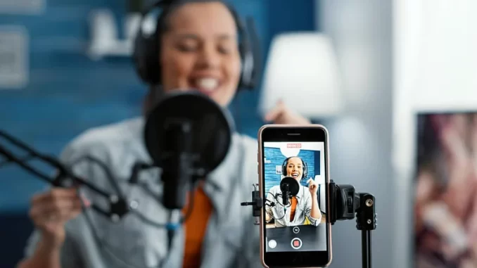 criadora-de-conteudo-grava-podcast-tiktok Criadora de conteúdo grava podcast de vídeo para TikTok, com equipamento de gravação profissional, promovendo lançamento de 25 podcasts em formato de vídeo.