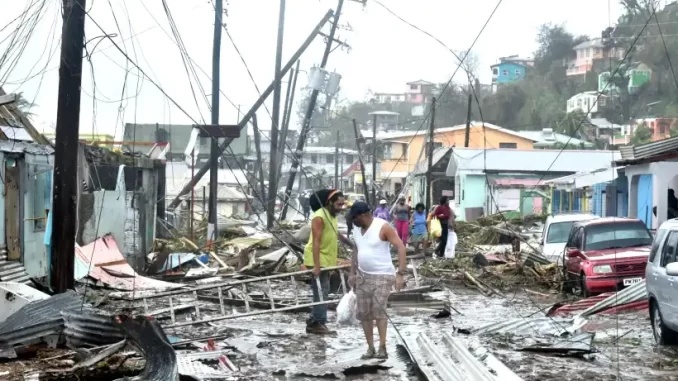 Avenida destruída por desastres climáticos com árvores, postes e veículos danificados, pessoas avaliando os danos e cenário de destruição em uma área urbanas afetada por desastres climáticos desde 2013.