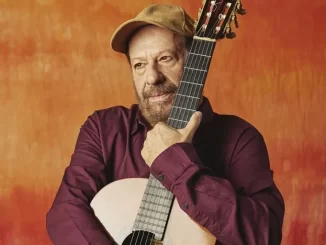 João Bosco, cantor brasileiro, segurando uma guitarra e usando boné, em fotos promocionais, voltando ao Circo Voador com seu novo álbum e sucessos musicais.