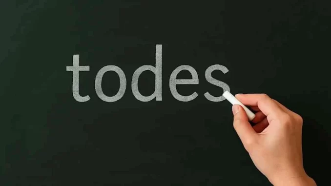 lula-da-silva-sancionou-lei-proibicao-linguagem-neutra-documentos-publicos Imagem de uma mão escrevendo a palavra "todes" na lousa, relacionada ao tema da proibição de linguagem neutra em documentos públicos sancionada por Lula da Silva.