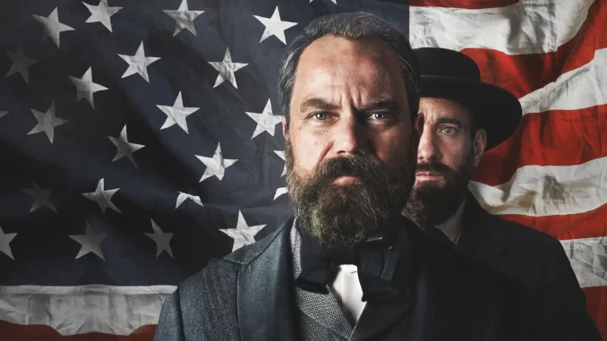 minisserie-com-um-relampago-netflix-morte-de-garfield Cena da minissérie da Netflix 'Como um Relâmpago' retratando um momento sombrio, com dois homens vestindo roupas antigas e uma bandeira americana ao fundo.