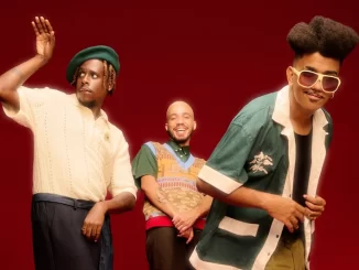 Os Garotin, grupo de músicos, ao vivo no Rio, durante a turnê Pro Brasil Cantar e Dançar, posando com alegria e energia em palco vermelho.